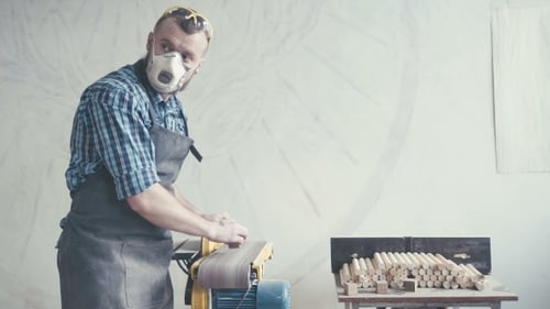 Man Sanding Wood in Workshop