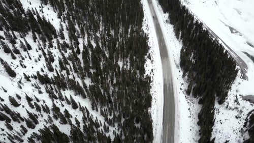Car Driving on Winter Road in Mountains During Snow Storm