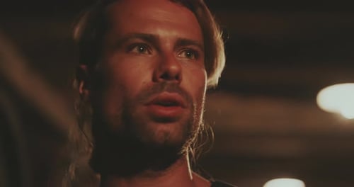 Man with Blonde Hair Talks in Dim Lighting