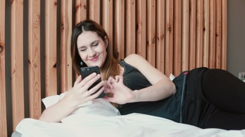Woman Using Smartphone Lying in Bed at Home