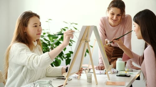 Profile View of a Couple of Adults Working on a Painting at an Art School