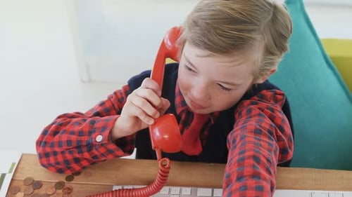 Young Boy Talking on Retro Telephone at Desk