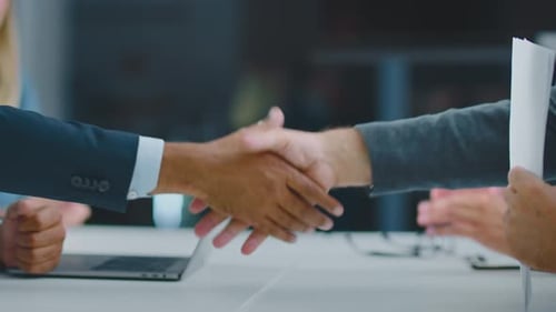 Handshaking over desk in office
