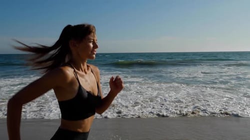 Athletic woman jogging along the beach