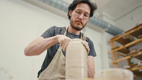 Professioneller männlicher Künstler, der Keramikvase kreiert, die mit Ton auf einer Töpferscheibe arbeitet, langsam