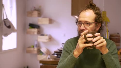 Man with Curly Hair Drinks from Mug Indoors