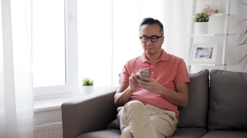 Man Relaxing on Sofa Using Smartphone