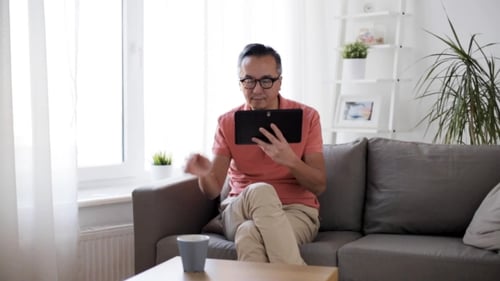 Man Using Tablet and Drinking Coffee at Home