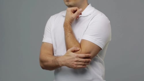 Man Rubbing Sore Elbow in Studio