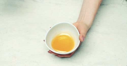 Woman Dripping Honey From Spoon Into Bowl