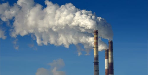 Industrial Smokestacks Emitting Plumes Against Blue Sky