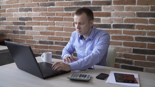 Man Works at Desk with Laptop and Calendar