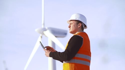 Energy Engineer of the Windmill To Work with the Tablet at Sunset. Environmental