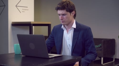 Young Adult Closing Laptop in Modern Workplace