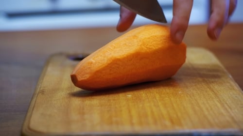 Cutting Carrots Into Slices on Chopping Board in Home Kitchen