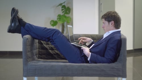 Man in Suit Relaxes on Couch with Laptop