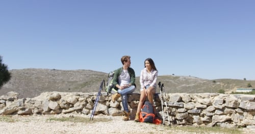 Couple Taking a Break on Stone Wall After Hike