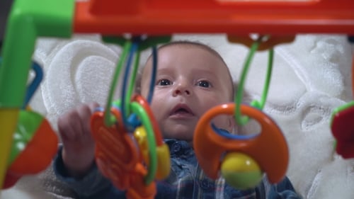 Cute Infant Gazes Up at Colorful Toys