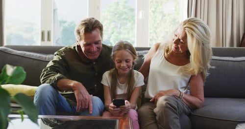 Girl Uses Phone With Family Together on Couch