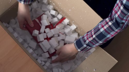 Hands Unpack Wrapped Gift from Box Indoors