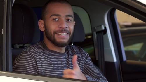 Young Adult Sits in Car and Gives Thumbs Up