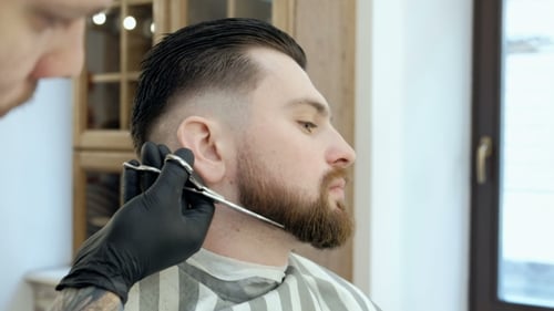Master Cuts Hair and Beard in the Barber Shop. Cut a Beard with Scissors