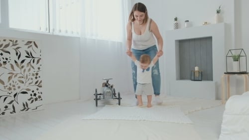 Cute Little Baby Is Looking at Camera and Smiling While Learning To Walk,