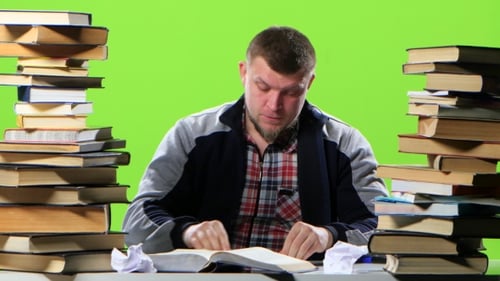Man Sitting at His Desk Writes His Notebook Information. Green Screen