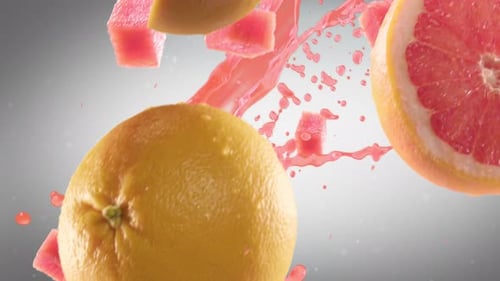 Pomelo con rodajas cayendo sobre fondo gris oscuro