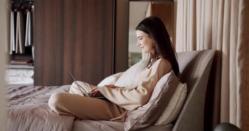 Frau arbeitet mit einem Laptop in ihrem Schlafzimmer Work From Home Concept
