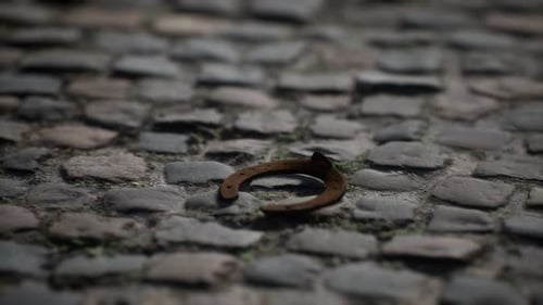 Rustic Rusty Horseshoe Slowly Rotating on Cobblestone Ground