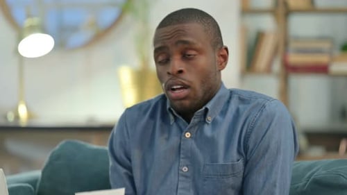 Sick Young African Man Sneezing at Home