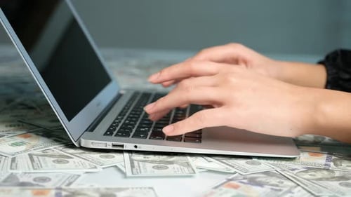 Typing on Laptop Covered in Hundred Dollar Bills