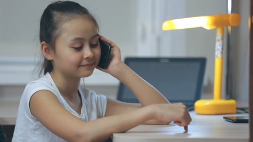 Smiling Girl Talking on Cellphone at Desk