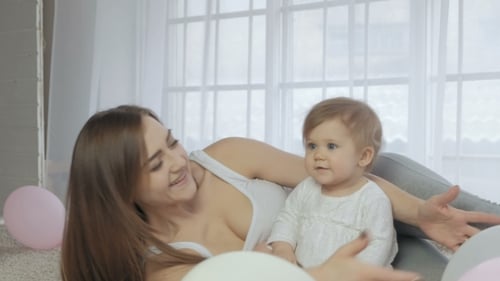 Smiling Mother and Baby Playing with Balloons