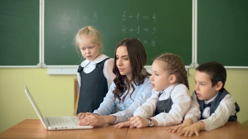 Teacher Helping Students with Laptop in Classroom