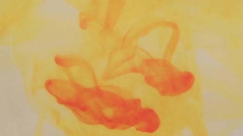 Colorant alimentaire jaune qui tourbillonne dans un récipient rempli d'eau.