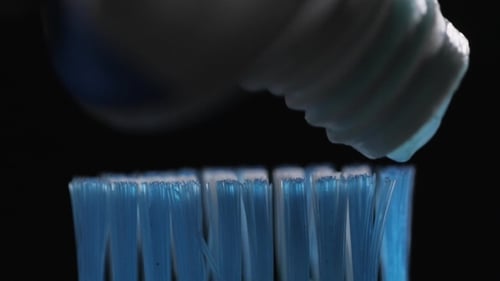Toothpaste Being Squeezed onto a Blue Toothbrush