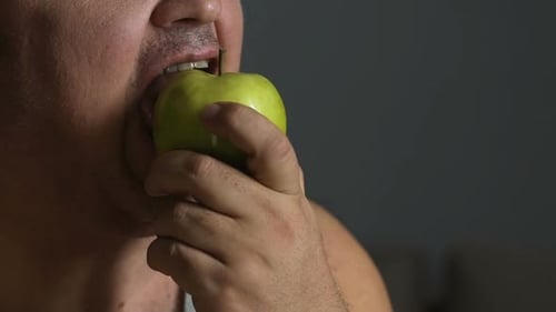 Man Takes Bite of Green Apple Close Up