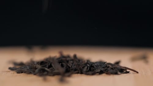 Black Dry Tea Leaves Isolated on Black Background Pouring Down