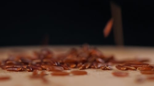 Red Rice Grains Falling on Wooden Surface
