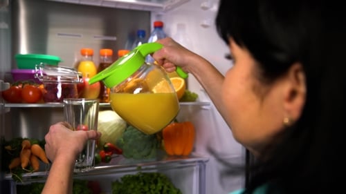 Woman Pours Fresh Orange Juice in Kitchen