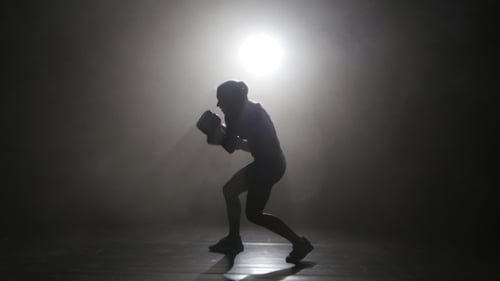 Champion Kickboxer Smoke échappe aux contre-coups de poing. Silhouette. Fond noir. Vue latérale