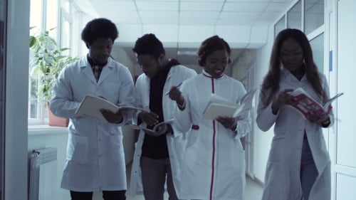 Medical Students Walking and Discussing in Hospital Hallway