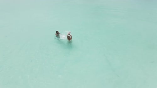 An Aerial View of a Happy Couple Swimming in the Crystal Clear Water Enjoying Beautiful Sea View