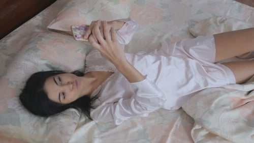 Woman Relaxing in Bed Using Smartphone