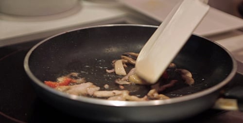 Sauteing Mushrooms and Peppers with Spatula on Cooktop