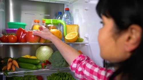 Woman Takes Apple from Refrigerator with Fresh Food