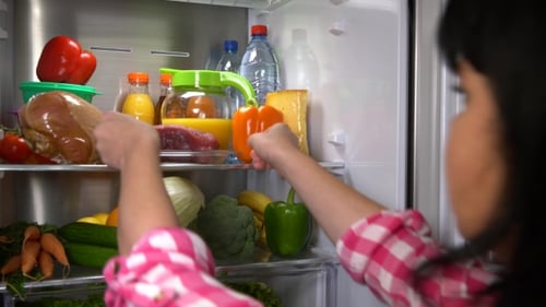Woman Placing Meat in Refrigerator with Food