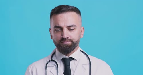 Serious Medical Doctor Shaking Head No After Contemplating, Blue Studio Background